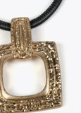 Gold-toned necklace with a black cord.
